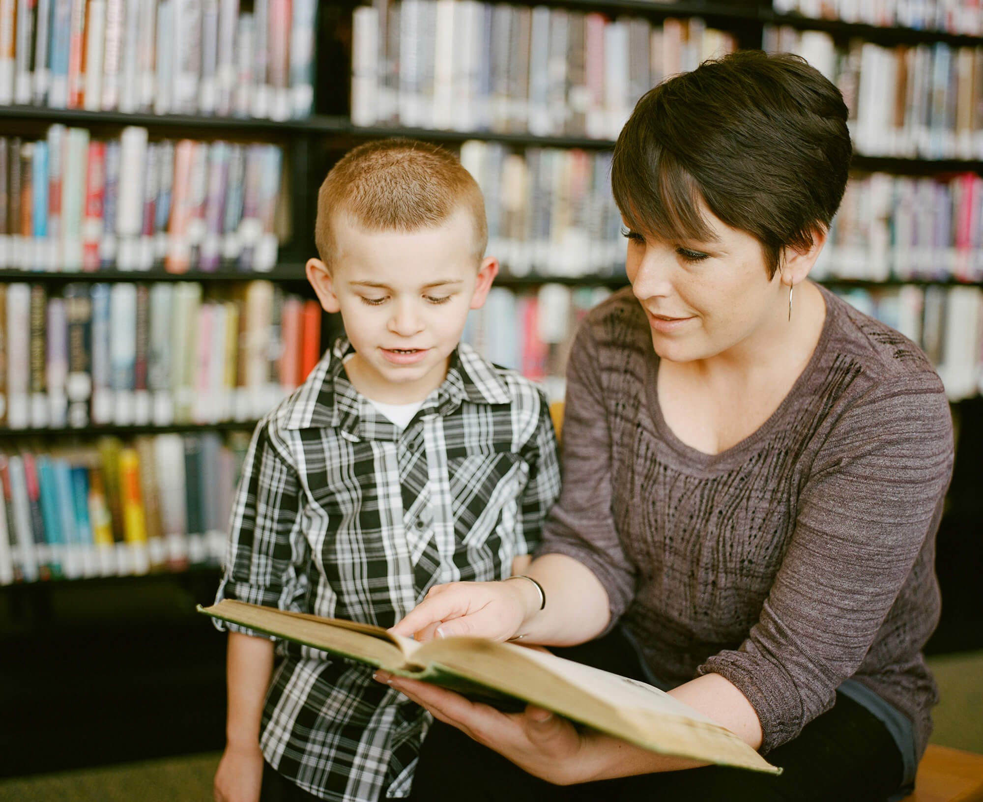 Educator reading a book with a young child in a library