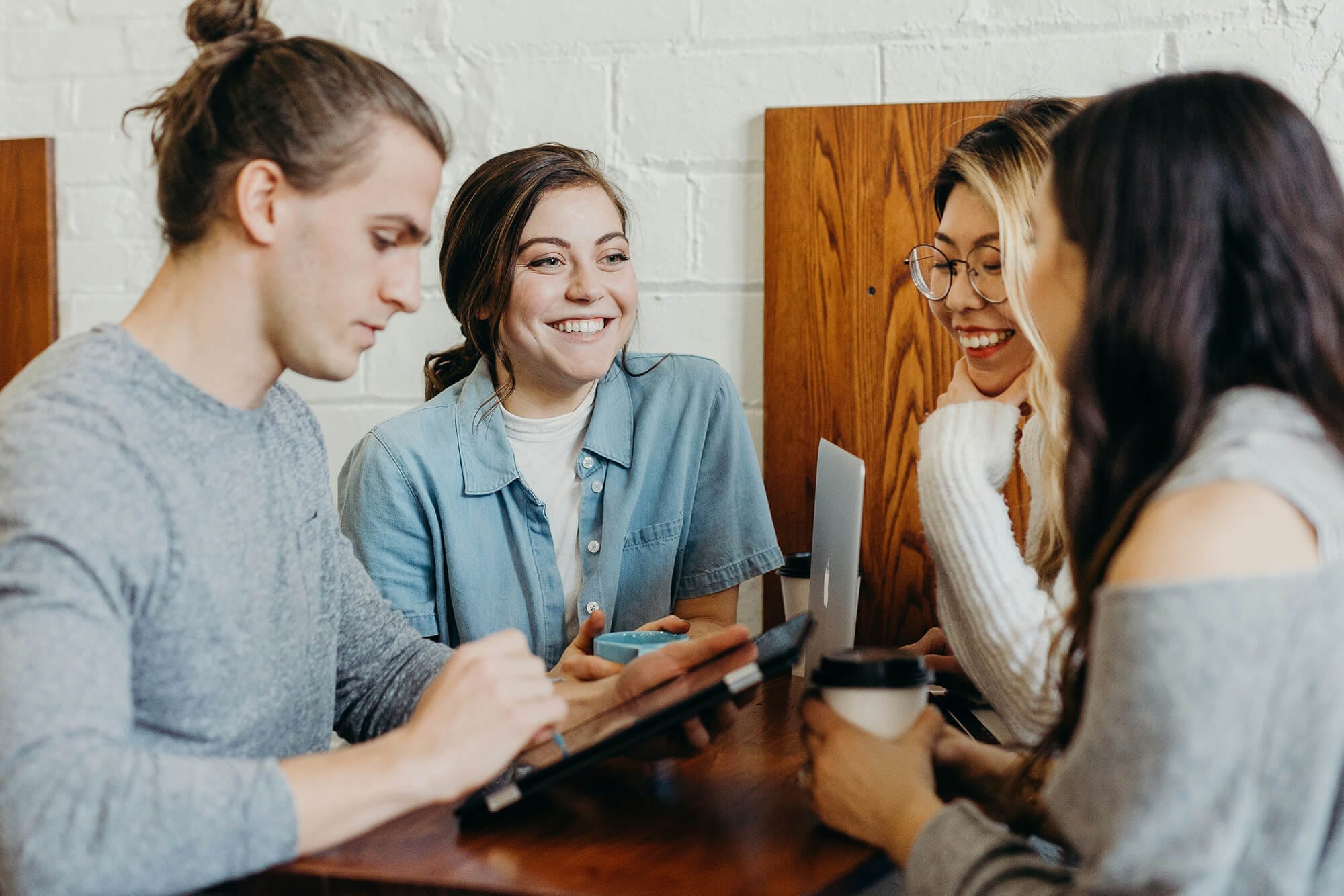 Four adults talking around a tablet in a coffee shop