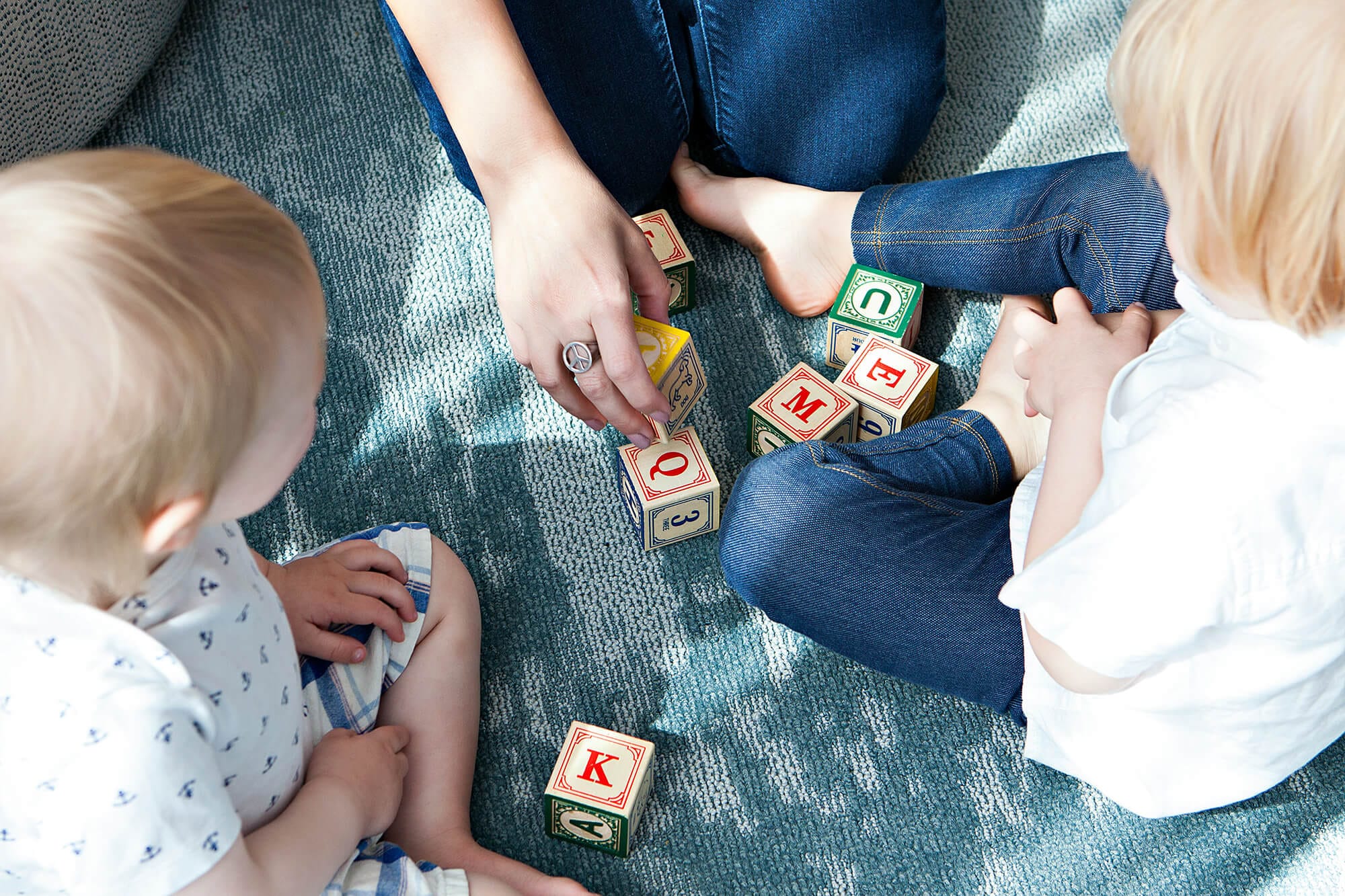 baby and young child playing with letter cubes with an adult